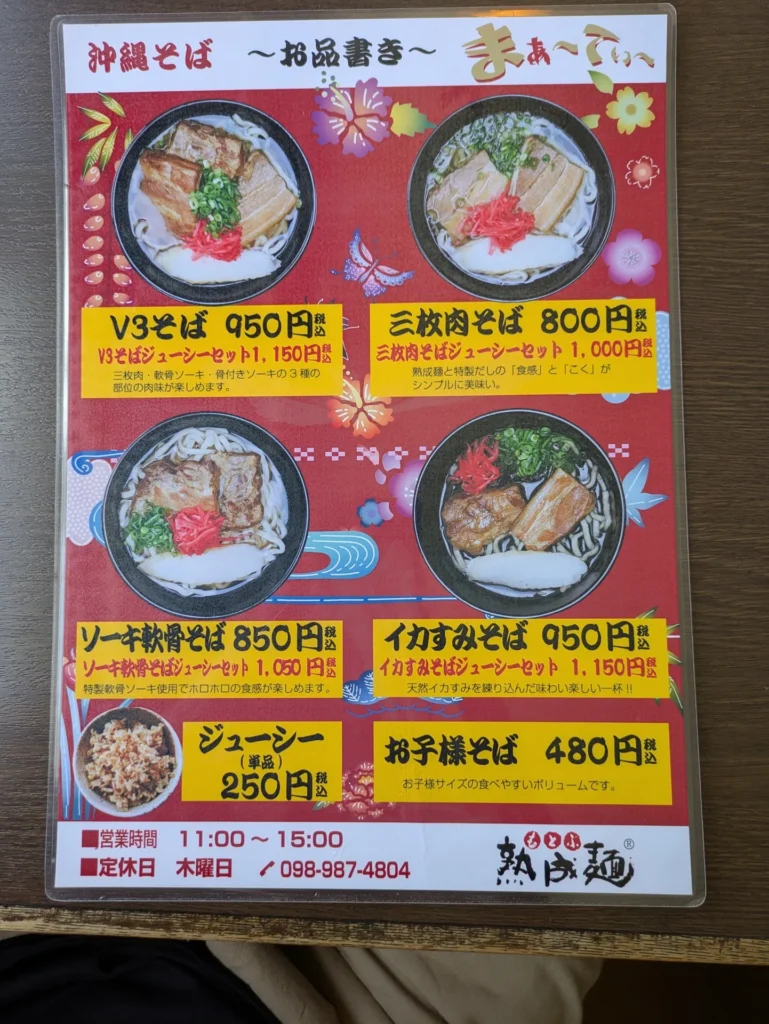まぁ〜てぃ〜の沖縄そばメニュー表。「V3そば」「三枚肉そば」「ソーキ軟骨そば」「イカすみそば」と価格、ジューシーセットの案内が記載されている。