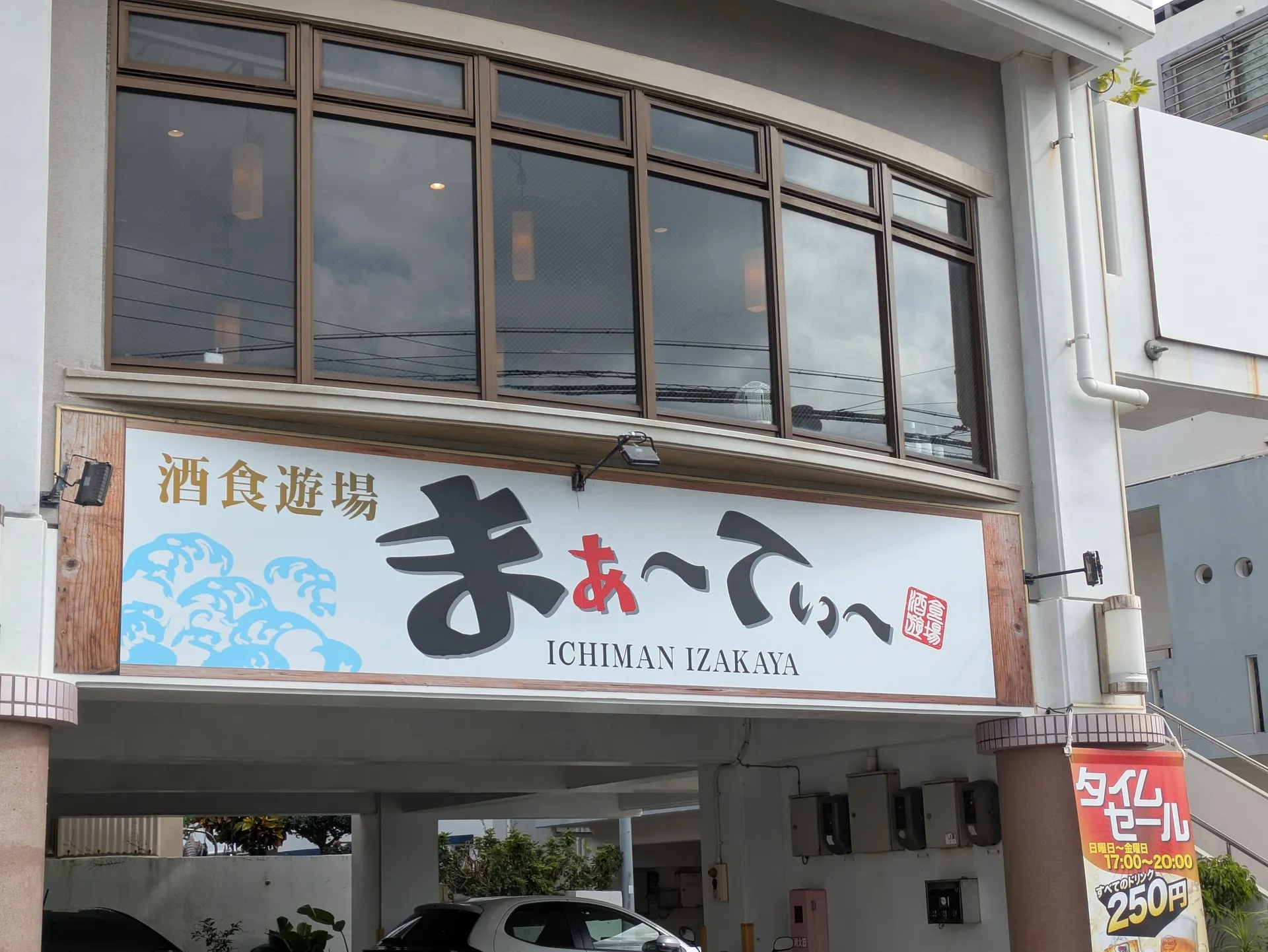 酒食遊場まぁ〜てぃ〜の店舗外観。波模様とICHIMAN IZAKAYAと書かれた大きな看板が目印。