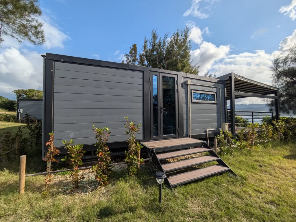グレーのコンテナヴィラ外観。ウッドデッキと大きな窓がある