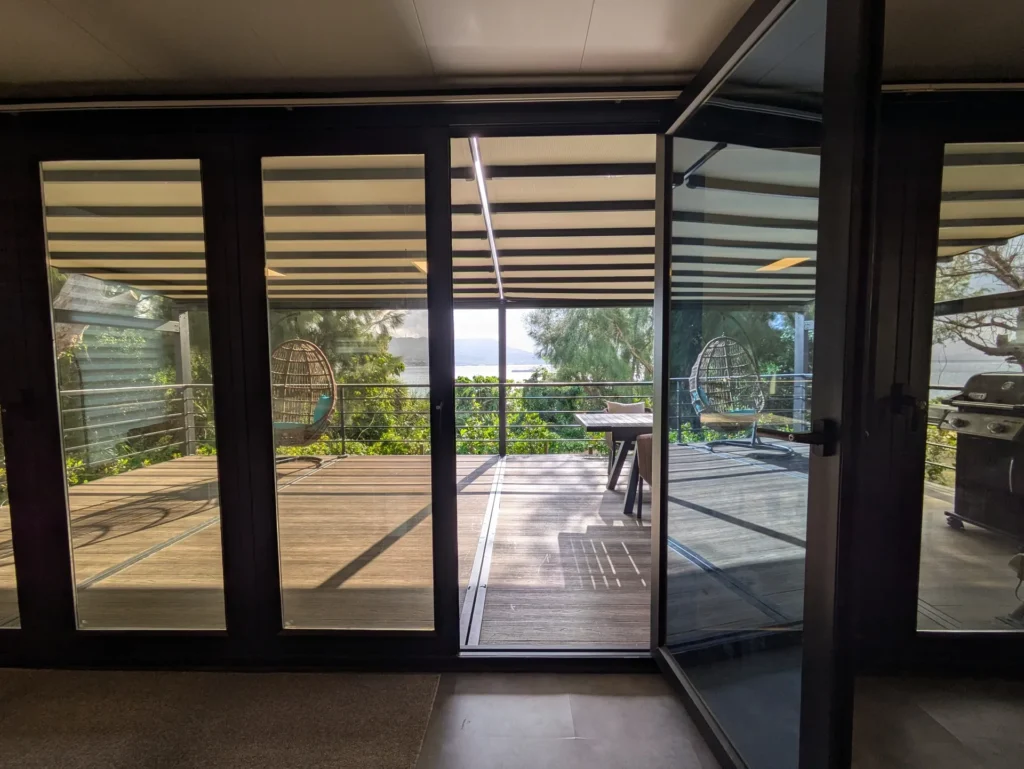 屋根付きのテラス席。テーブルセットとBBQグリル、ハンギングチェアがある