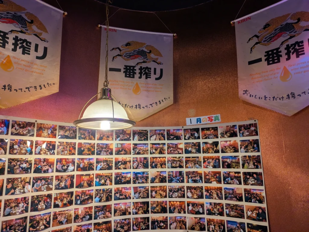 キリン一番搾りの大きな垂れ幕と、壁一面に貼られた来店客の記念写真