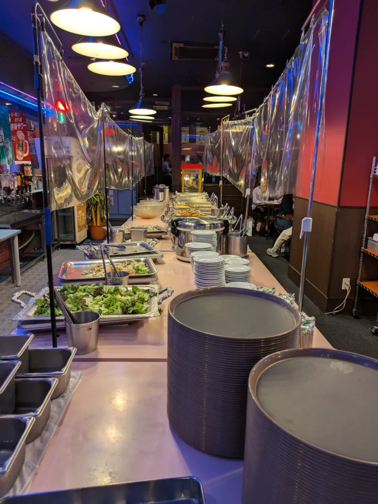 バイキング居酒屋リオの店内に並ぶ、サラダや温かい料理が用意されたセルフサービスのバイキングカウンター