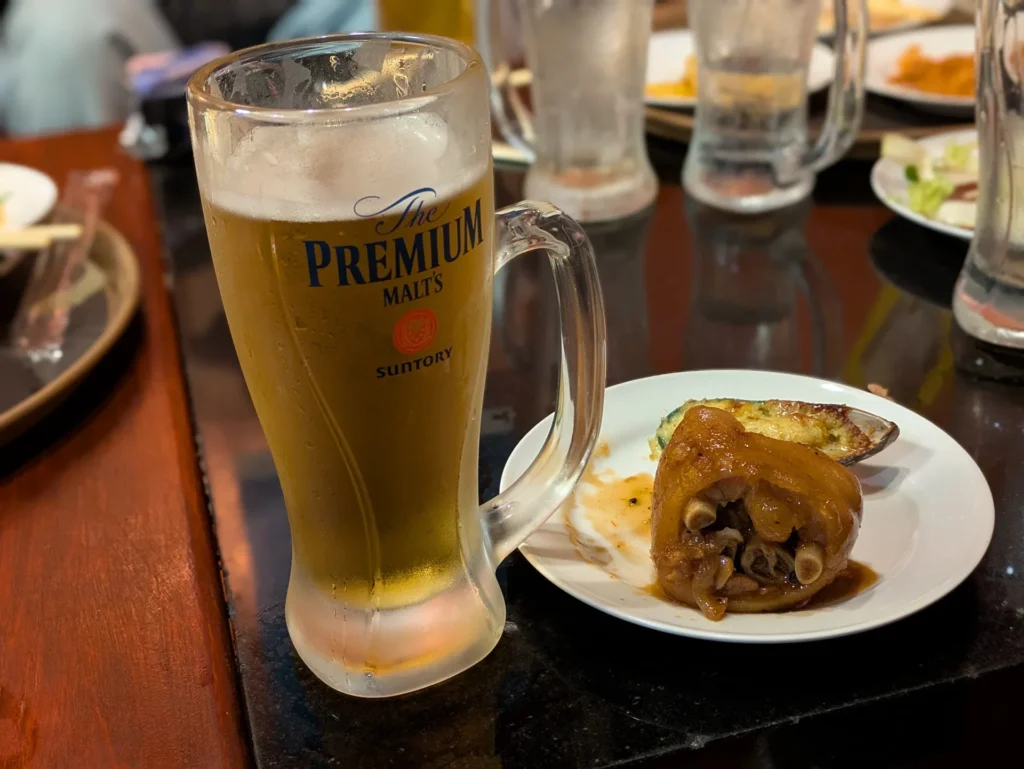 バイキング居酒屋リオの冷えたプレミアムモルツの生ビールと、沖縄名物の豚足(テビチ)の煮付け
